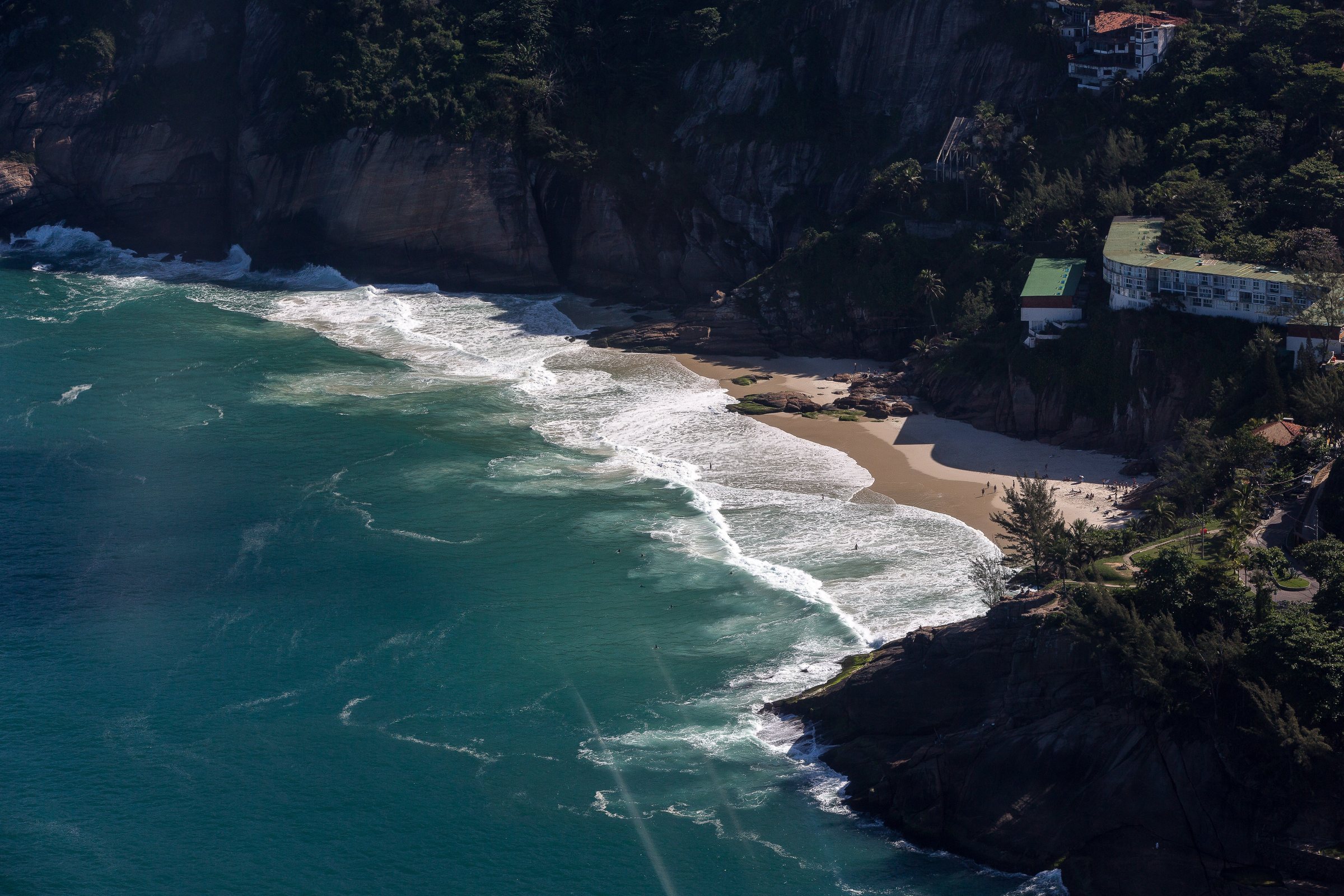 Praia da Joatinga from the air — a crescent of sand hemmed by granite, reachable on foot at low tide.